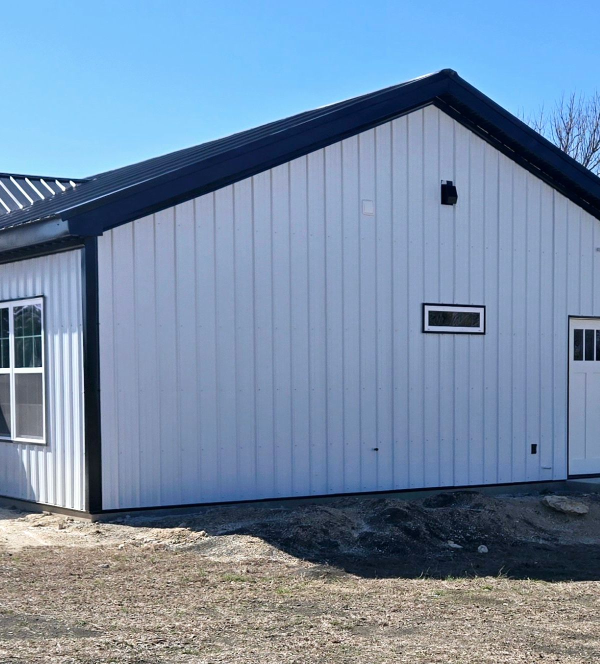 White exterior with black metal roof and timber porch